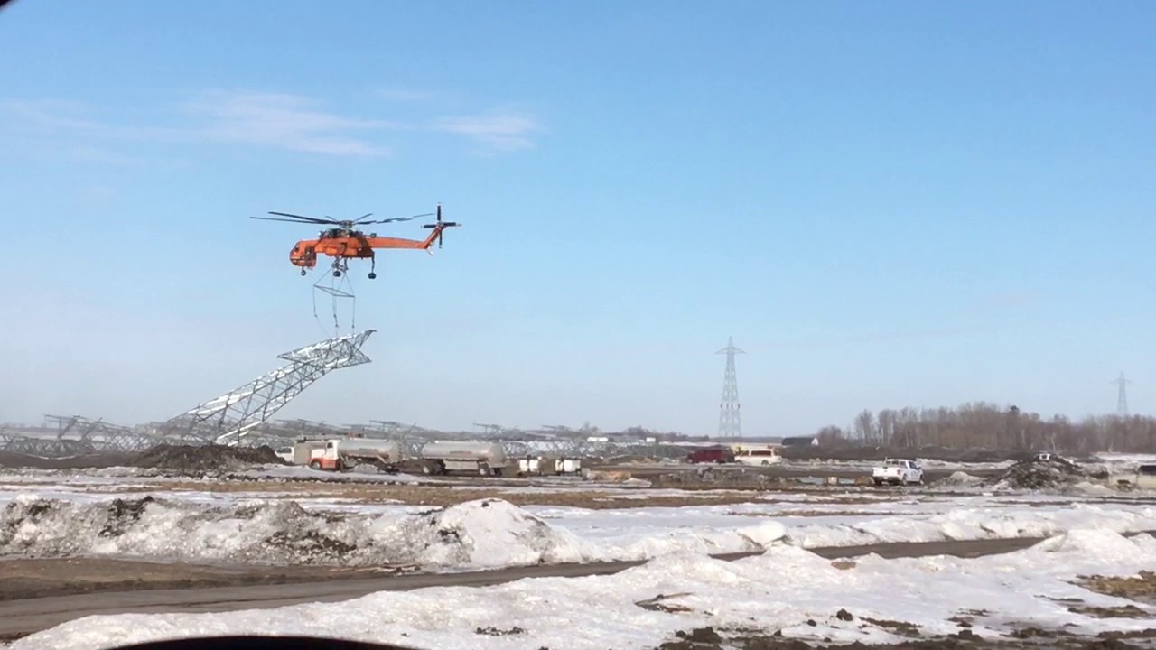 Helicopter picking up power line tower 